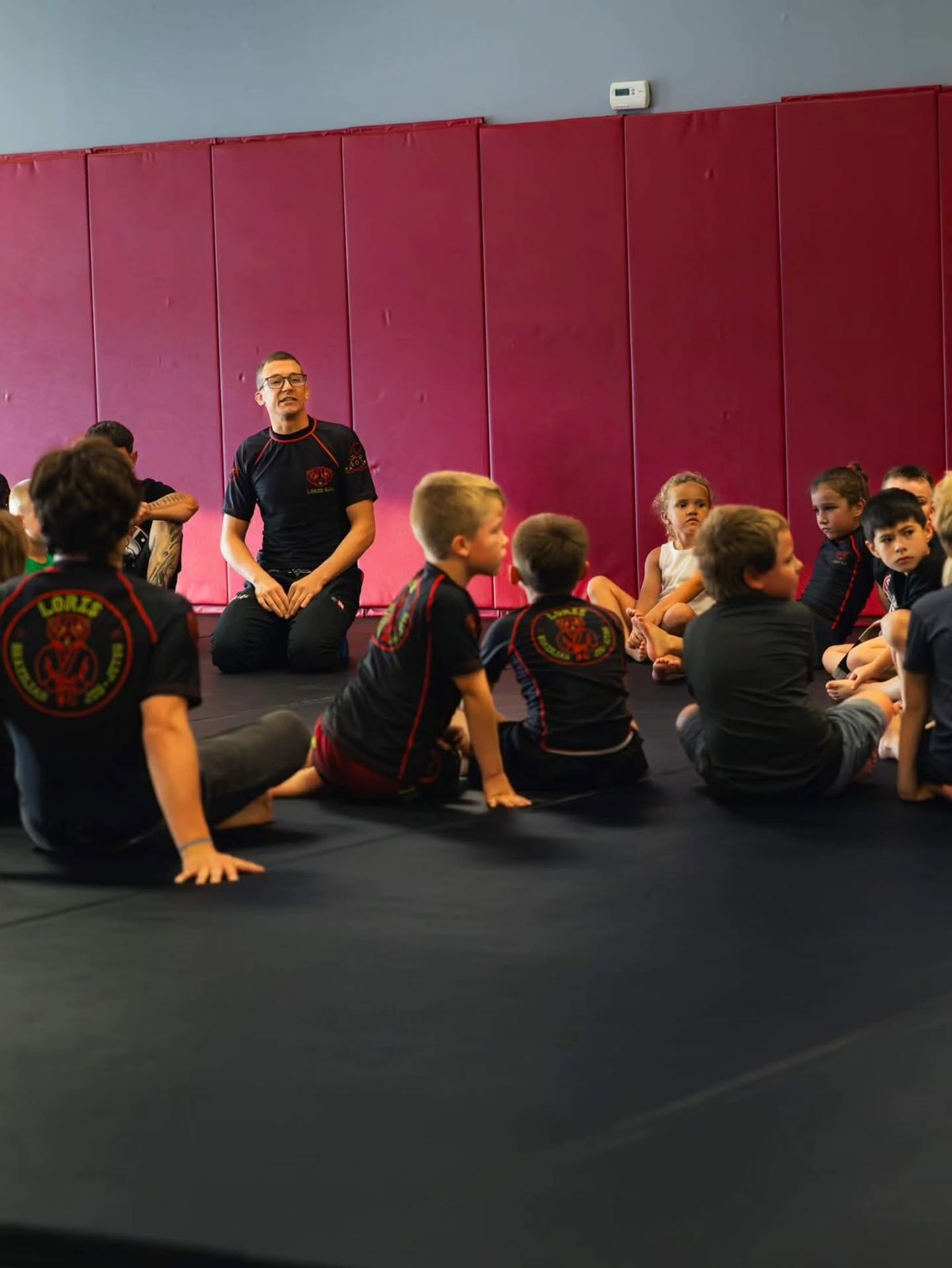 Instructor talking to a group of young children during a kids Jiu-Jitsu class